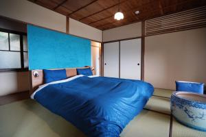 热海new! 熱海桃山邸　Atami terrace villa 〜Sauna & Onsen 〜的一间卧室设有蓝色的床和蓝色的墙壁