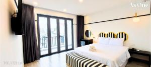边和As ONE Hotel Biên Hòa的卧室设有白色的床和大窗户