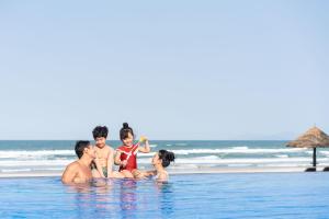岘港Danang Marriott Resort & Spa的坐在海滩游泳池的家庭