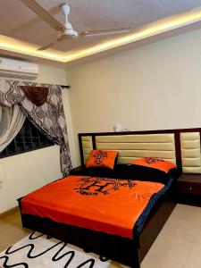洛美S2A apparts的一间卧室配有一张带橙色毯子的床