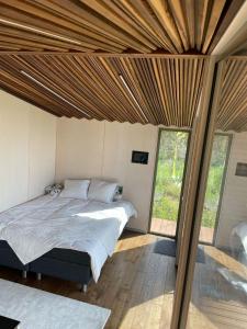 Looduskeskne Olivia moodulmaja Põltsamaal的卧室配有一张床铺,位于带滑动玻璃门的房间