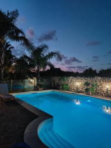 奇尼斯Villa Manzella piscina privata的夜间游泳池,设有岩石墙
