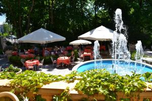 奥格斯堡格拉迪亚拖勒旅馆的花园内的喷泉,花园内设有桌子和遮阳伞
