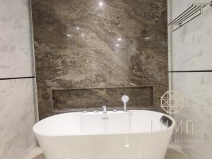 吉隆坡The Platinum 2 Kuala Lumpur by LUMA的浴室配有白色浴缸及石墙