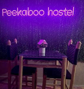 马拉喀什Peekaboo Hostel的一张桌子,两把椅子和一个紫 ⁇ 虹灯标志