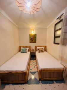 马拉喀什Peekaboo Hostel的配有吊灯的小客房内的两张床