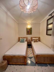马拉喀什Peekaboo Hostel的配有吊灯的客房内的两张床
