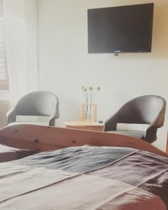 MüllenbachFerienwohnung Funk的卧室配有两把椅子和墙上的电视。