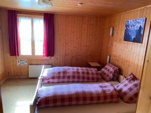 盖尔绍Rigi-Burggeist Alpine Guesthouse的一间带两张床铺的卧室,位于带木墙的房间内