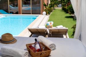 阿特米达Modular Bungalows With Heated Pool Artemis Greece的游泳池畔桌子上一篮葡萄酒和一顶帽子