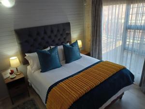 德尔斯特鲁姆Cinnamon & Sage Country Cabins的一间卧室配有一张带蓝色枕头的大床和窗户。