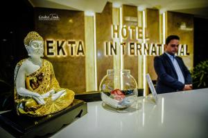 德奥加尔Hotel Ekta International的身穿西装的男人站在女人的雕像旁边