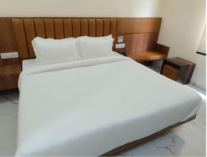 穆扎夫法尔普尔Hotel Paramveer的一张配有白色床单和木制床头板的大床