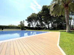 坎布里尔斯LuxuryCambrils Resort&Spa的棕榈树旁的带木甲板的游泳池
