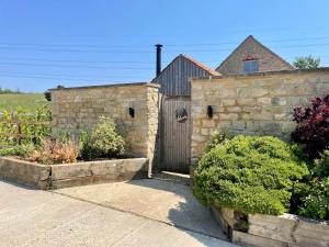 Little BythamThe Cow Shed - Rural Barn Conversion的石头建筑,设有木门和灌木丛