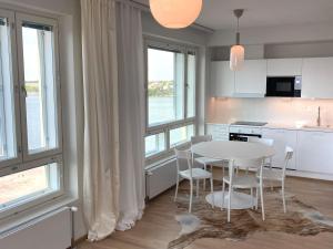 赫尔辛基Goldfinger saunallinen kaksio merinäköalalla 11 krs的厨房配有白色的桌子、椅子和窗户。