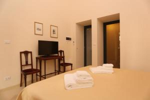 库特罗菲安诺Villa Lucrezio Resort的一间卧室配有一张床、一台电视和毛巾