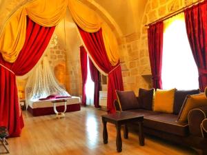 马尔丁Tuğhan Hotel的客厅配有红色窗帘和沙发