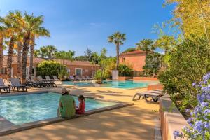 滨海阿热莱斯魔松树露营酒店的坐在游泳池旁的男人和孩子
