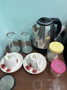 加尔各答Teakwood Suite - Nokha House的一张桌子,上面放着两个盘子和茶壶