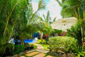 格兰贝伊Preety Blue Residence villas的一个带长凳和遮阳伞的花园以及一个游泳池