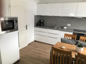 埃肯弗德Ferienhaus Kader的厨房配有白色橱柜和桌椅