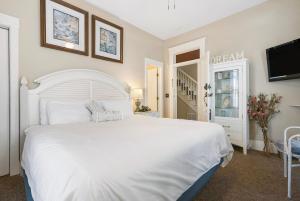 布兰森Historic Branson Hotel - Quiet Quilt Room with King Bed - Downtown - FREE TICKETS INCLUDED的卧室配有白色的床和电视
