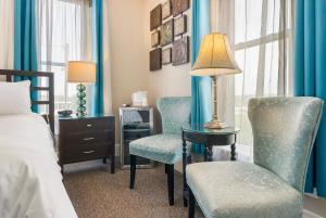 布兰森Historic Branson Hotel - Serendipity Room with Queen Bed - Downtown - FREE TICKETS INCLUDED的一间卧室配有两把椅子和一张带台灯的桌子