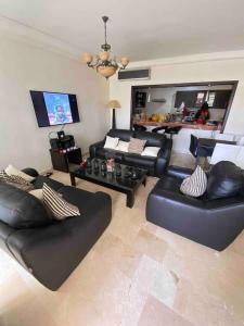 阿加迪尔Luxueux appartement à la Marina d’agadir的客厅配有黑色皮革家具和平面电视