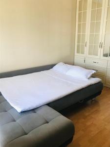 阿拉木图Уютная, ухоженная квартирка.的卧室里一张带白色床单和灰色箱形凳的床