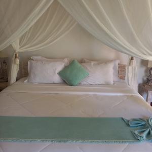 RuaRua Beach Resort Sumba的一张带白色枕头和天蓬的床