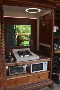 凯阿奥The Red Cottage and Hawaiian Pond Garden Paradise!的厨房配有炉灶和微波炉,位于柜台上