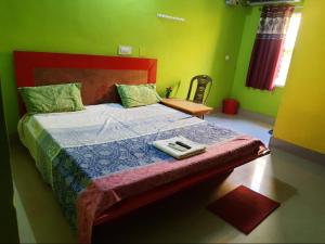 科纳卡Goroomgo Sun Plaza Lodge konark的一间卧室配有一张带红色床头板和绿色墙壁的床。