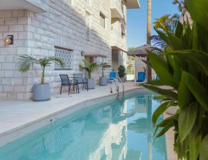 伯利恒Dar Al Mauge Boutique Hotel with Outdoor Pool的一座带桌椅的游泳池位于酒店大楼旁