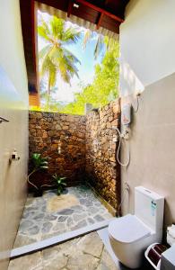 达瓦拉维Mango Tree House的一间带卫生间和石墙的浴室