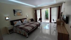 杜马格特Villa Shangri-La的一间卧室配有一张床、一张书桌和一个窗户。