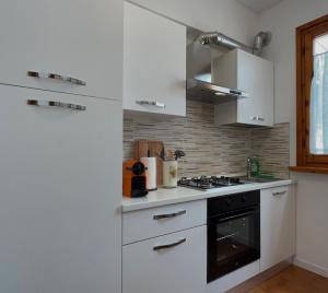 维亚雷焦Villino Anna的厨房配有白色橱柜和炉灶烤箱。
