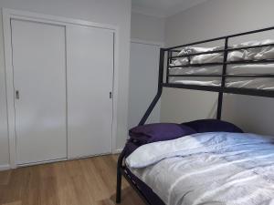 墨尔本Maruve Guesthouse 12 min from Melb airport的一间卧室配有一张黑色双层床和一个衣柜