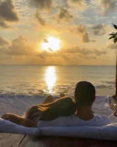 江比阿Natural Garden Hotel的坐在热水浴缸中的男人和女人,看着日落