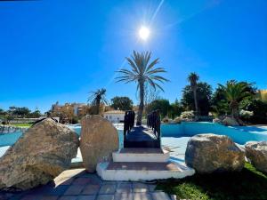 滨海罗克塔斯Beachfront apartment in Roquetas de Mar with communal pool的一个带岩石和棕榈树的游泳池的度假酒店