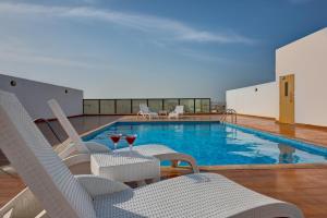 迪拜City Stay Residences - Serviced Apartments DIP的一个带椅子和桌子及酒杯的游泳池