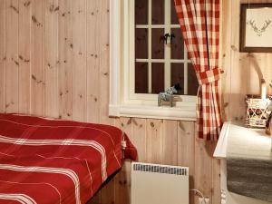 Holiday home Engerdal的一间卧室设有木墙和一个带红色毯子的窗户。