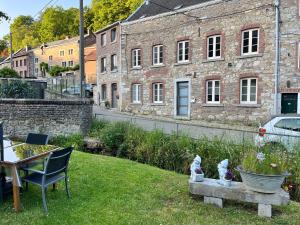 OlneCharmante petite maison à Olne的一个带椅子的院子和一座石头建筑