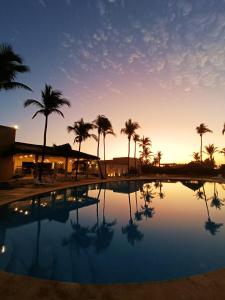 Barra Vieja阿卡普尔科第三生命酒店的日落前种有棕榈树的游泳池