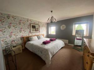 班戈Carreg Y Garth Isaf - Hot Tub Nr Zip World的一间卧室配有一张粉红色花卉壁纸的床