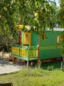AudelangeLa roulotte de moulin rouge的绿黄房子,树下有两长椅