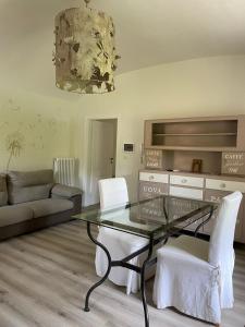 阿维利亚纳Novecento Charming Room的客厅配有玻璃桌和白色椅子
