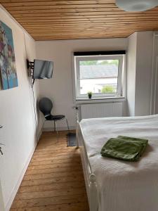 洛肯Fru Hald的一间卧室设有一张床、一个窗口和一把椅子