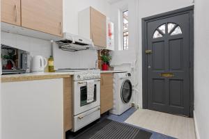 伦敦Fantastic 2BD Barking stay with links to the City!的厨房设有黑色的门和一台洗衣机