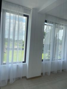 巴亚德菲耶尔La Scoabă的一间设有白色窗帘和大窗户的客房